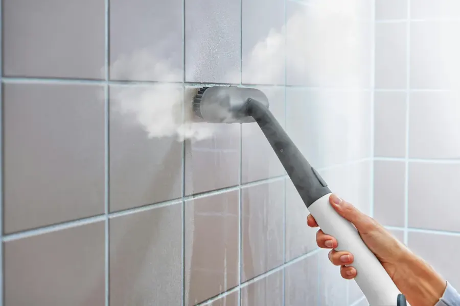 Steam cleaner nozzle cleaning white wall tile and grout lines